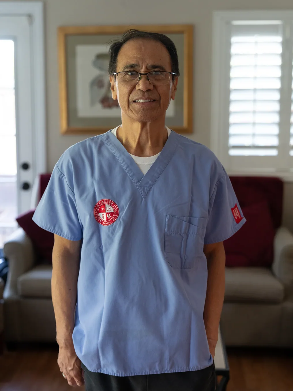 Caregiver in medical scrubs standing in residential care home living room